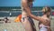 Mother in bikini apply sun protection sunscreen cream on daughter girl back
