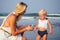 Mother blonde in a white dress and fair-haired one year old daughter use an antiseptic antibacterial gel on the beach