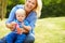 Mother Blowing Bubbles For Young Boy In Garden