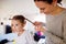 Mother braiding hair of her daughter in the morning