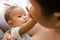 Mother breastfeeding her newborn baby beside window