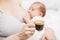 Mother breastfeeding newborn baby drinking coffee