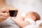 Mother breastfeeding newborn baby drinking coffee