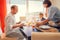 Mother brings a dish of meal at table to her hungry family