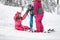 Mother and brother learns girl to get up from snow with skis