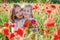 Mother brunette in white with daughter together on blossoming red poppies field