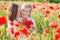 Mother brunette in white with daughter together on blossoming red poppies field