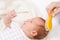 Mother brushing hair of newborn baby with natural bristle brush