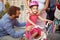 Mother buying at happy girl bicycle helmet in bike shop