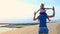 Mother Carries Small Girl on Shoulders on Dunes at Sunset