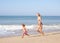 Mother chasing young girl on beach