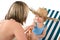 Mother with child apply suntan lotion on beach
