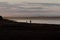 Mother and child as silhouettes in the sunset exploring and unknown land by the sea