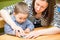 Mother and child boy drawing together with color pencils in preschool at table in kindergarten