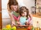 Mother with child daughter preparing fish in