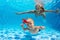 Mother with child dive underwater in swimming pool