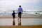 Mother and Child Holding Hands Walking on Beach