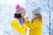 Mother and child in knitted winter hats in snow