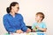 Mother and child learning math at the desk in white interior room. Private tutor and kid at lesson