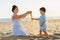 Mother with child play with sand on sea beach