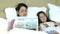 Mother and child reading newspaper in bed having fun