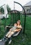 Mother and child ride on a wicker rattan cocoon swing. son shakes a woman, shakes a summer vacation in nature