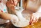 Mother and child sieving flour