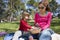 Mother and child sitting in park sharing pasta