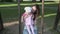 Mother with child swinging on wooden swing in green park outside
