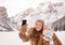 Mother and child taking selfie among snow-capped mountains