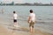 Mother and child walking on a sandy beach. Cool water in the sea. Walk along the beach barefoot. Cool in the summer in the heat.