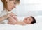 Mother and child on white bed. Parent and little kid relaxing at home. Mom doing massage baby.