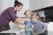 Mother with children baking and tasting cookie batter in kitchen