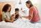 Mother and children browsing a digital tablet in the bed at home, bonding and learning to use technology. Family on the