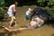 Mother with children caressing Asian elephant in captivity, chained, abused for attracting tourists