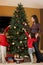 Mother And Children Decorating Christmas Tree