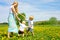 Mother and Children Playing and Dancing Outside in Flower Meadow