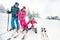 Mother with children on ski terrain preparing daughters ski shoe