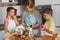 Mother and children together making apple pie in the kitchen at home. Children helping mother