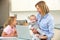 Mother with children using laptop in kitchen