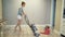 Mother clean dust from the floor with a vacuum cleaner and a little child`s daughter are playing near.