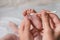 Mother cleaning baby`s foot with cotton bud on blurred background, closeup