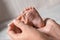 Mother cleaning baby`s foot with cotton bud on blurred background, closeup