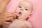 Mother cleaning baby`s mouth with special fingertip brush