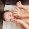 A mother cleans her nose with a cotton swab to a happy toddler baby b