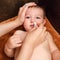 A mother cleans her nose with a twisted cotton pad to a happy toddler