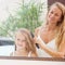 Mother combing daughter hair