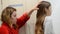Mother combs her little daughter`s long hair with a comb