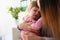 Mother consoles crying baby girl home closeup