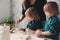 Mother cooking with kids in kitchen. Toddler siblings baking together and playing with pastry at home